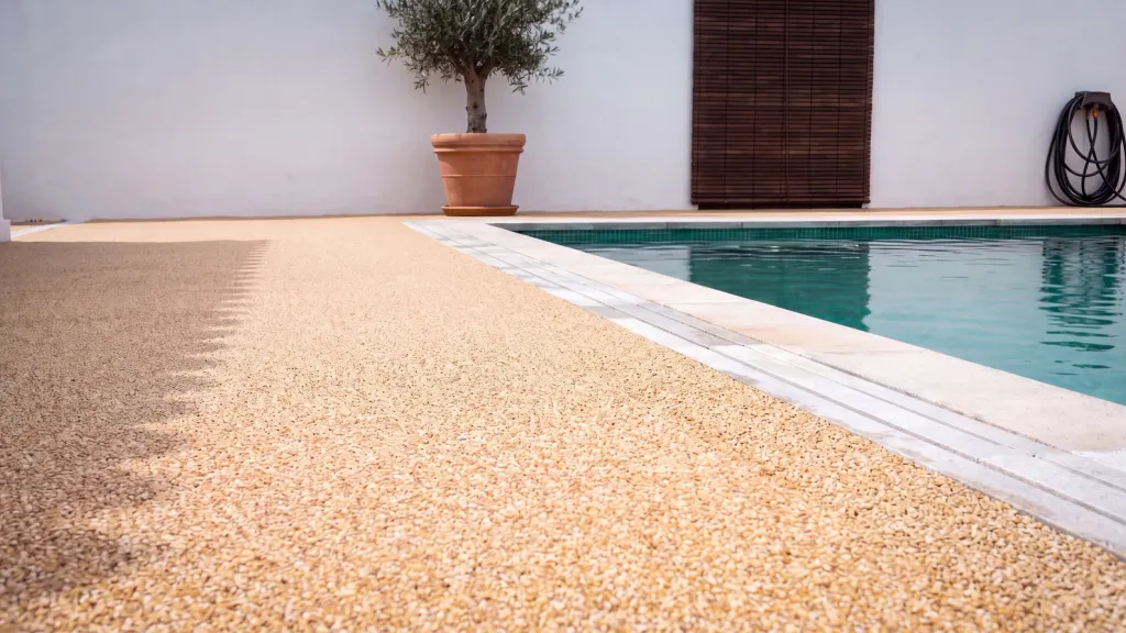 Terraza junto a piscina con stone carpet: pavimento continuo de árido en primer plano