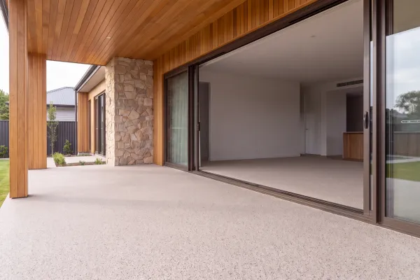 Porche cubierto con stone carpet junto a puertas correderas, pavimento continuo en primer plano